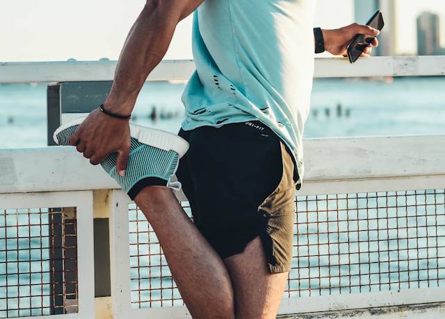 Runner doing a dynamic warm-up exercise along a park path